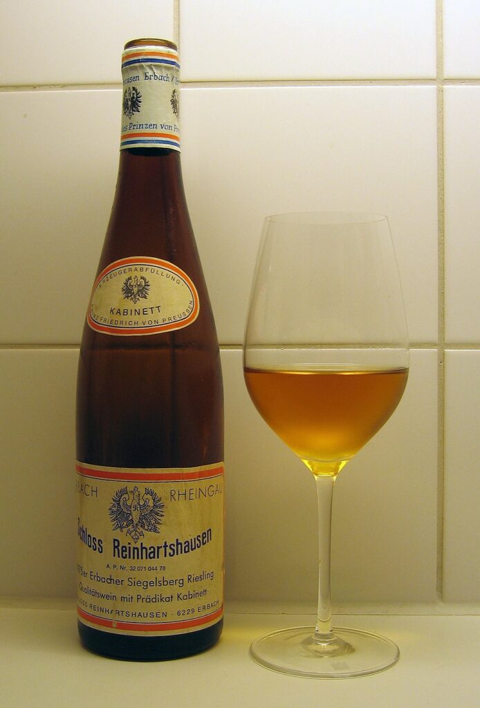 Bottle of Riesling Kabinett wine beside a filled glass, showcasing the wine's light color and clarity.